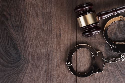 A gavel and handcuffs on a wooden table